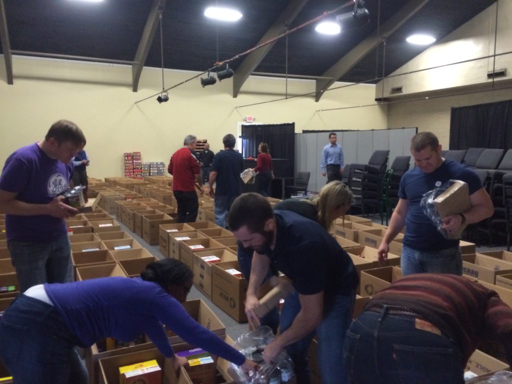 (Top) Summer food packs, given to families with children during the summer months, generously donated by the Presbyterian Church of Wyoming (Bottom) Volunteers donating their time to pack holiday food boxes with donated food for the Holiday Sharing program